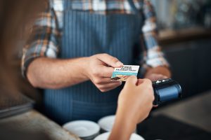 Closeup shot of a unrecognizable person giving a barman a credit card as payment inside of a restaurant